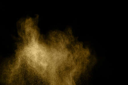 Golden powder explosion on black background. Freeze motion.