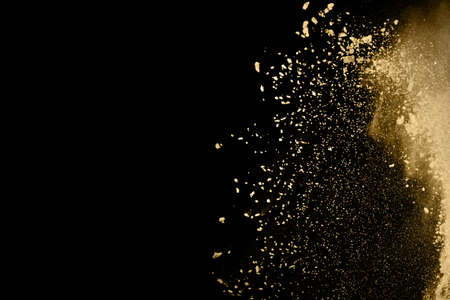 Golden powder explosion on black background. Freeze motion.