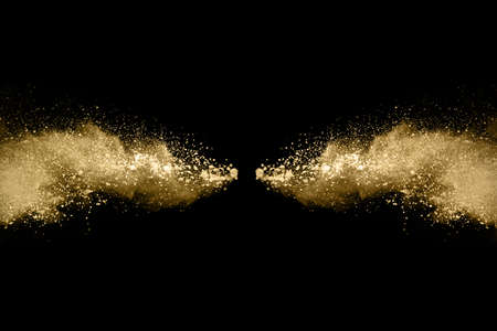 Golden powder explosion on black background. Freeze motion.