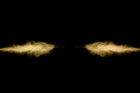Golden powder explosion on black background. Freeze motion.