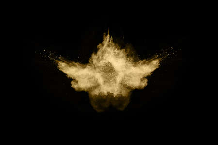 Golden powder explosion on black background. Freeze motion.