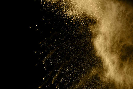 Golden powder explosion on black background. Freeze motion.