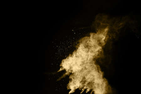 Golden powder explosion on black background. Freeze motion.