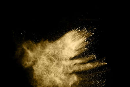 Golden powder explosion on black background. Freeze motion.