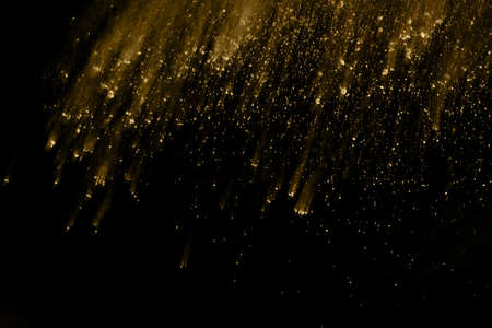 Golden powder explosion on black background. Freeze motion.