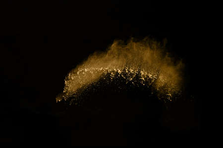 Golden powder explosion on black background. Freeze motion.
