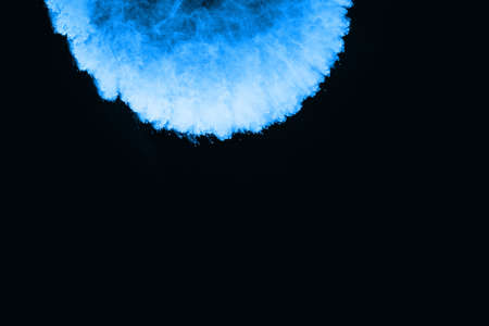 Blue powder explosion on black background. Colored cloud. Colorful dust explode. Paint Holi.の写真素材
