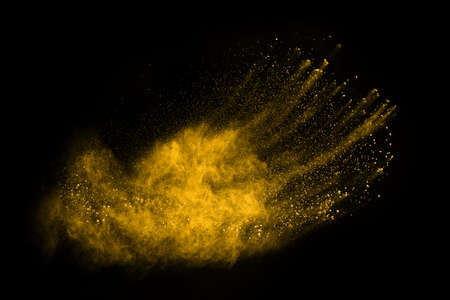 Freeze motion of yellow dust explosion isolated on black background.の写真素材