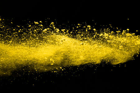 Freeze motion of yellow dust explosion isolated on black background.