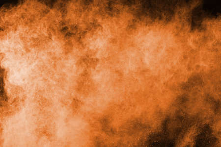 Freeze motion of orange powder exploding, isolated on black background. Abstract design of red dust cloud.の写真素材