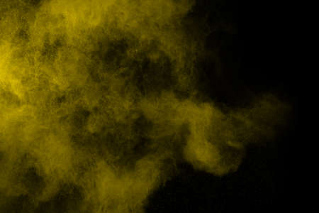 Freeze motion of yellow dust explosion isolated on black background.の写真素材