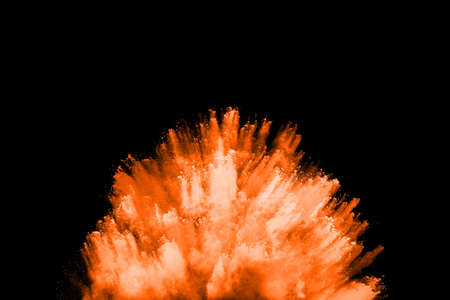 Freeze motion of orange powder exploding, isolated on black background. Abstract design of red dust cloud.の写真素材