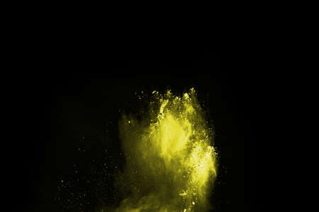 Freeze motion of yellow dust explosion isolated on black background.