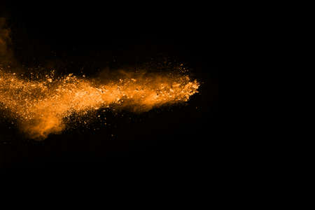 Orange powder explosion on black background. Colored cloud. Colorful dust explode. Paint Holi.の写真素材