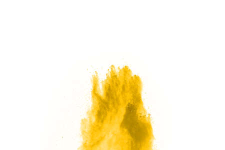 Powder explosion. Closeup of a yellow dust particle explosion isolated on white. Abstract backgroundの写真素材