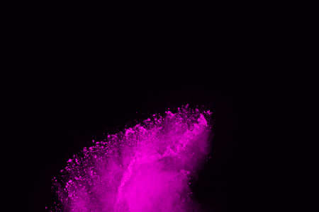 Pink powder explosion on black background. Colored cloud. Colorful dust explode. Paint Holi.