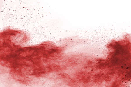 Freeze motion of red powder exploding, isolated on white background. Abstract design of red dust...