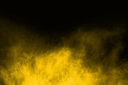 Freeze motion of yellow dust explosion isolated on black background.の写真素材