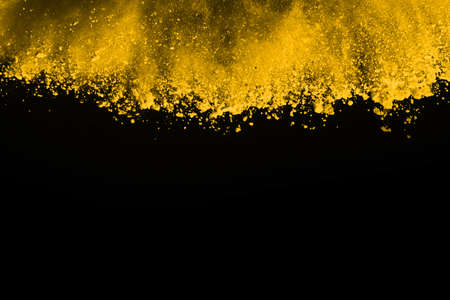 Freeze motion of yellow dust explosion isolated on black background.