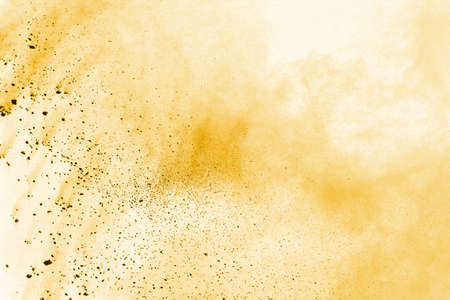 Powder explosion. Closeup of a yellow dust particle explosion isolated on white. Abstract background