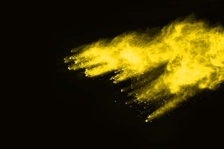 Freeze motion of yellow dust explosion isolated on black background.の写真素材