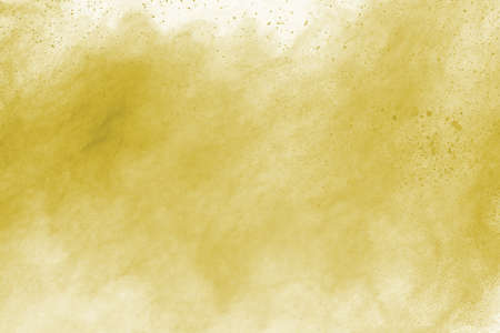 Powder explosion. Closeup of a yellow dust particle explosion isolated on white. Abstract background