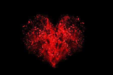 Red explosion of powder in the form of a heart on a black background.の写真素材