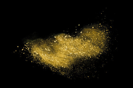 Gold powder explosion isolated on black background. Golden dust splash on black background.の写真素材