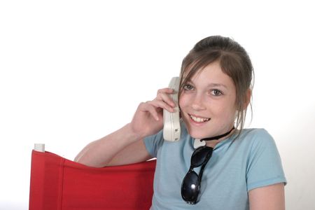 Cute young teenage girl sitting in a chair and talking on a cellphone; shot on whiteの写真素材