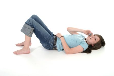Cute young teenage girl sitting on the floor and talking on a cellphone; shot on whiteの写真素材