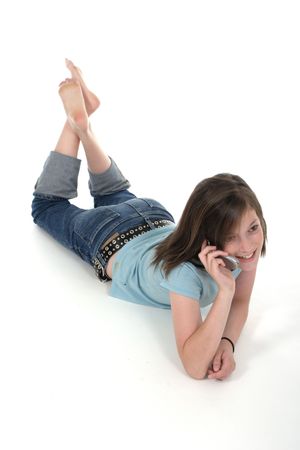 Cute young teenage girl sitting on the floor and talking on a cellphone; shot on whiteの写真素材