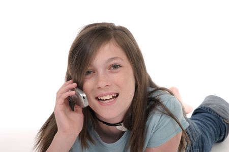 Cute young teenage girl sitting on the floor and talking on a cellphone; shot on whiteの写真素材
