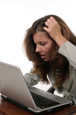 Attractive executive business woman working on a laptop computer frustrated with work.