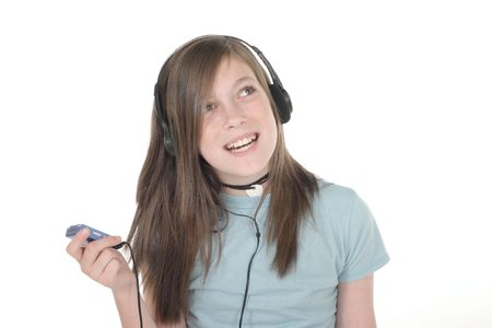 Cute, smiling, young teenage girl standing and listening to music with headphones and mp3 player; shot on whiteの写真素材