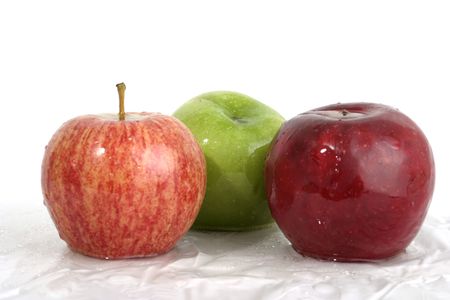 Three wet apples; one red, one green, one speckled red with water droplets on them.の写真素材
