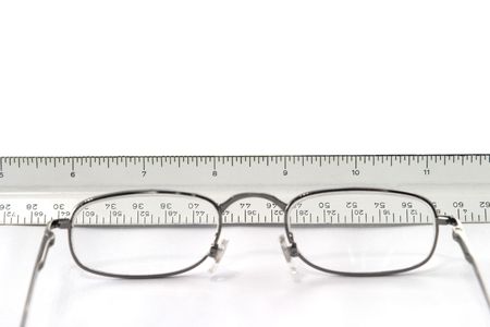 reading eyeglasses and ruler placed on table; the glasses are in the foreground and are out of focus; the ruler can be seen through the glasses; focus is on the rulerの写真素材
