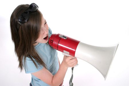 Young pre teen or tween girl shouting, speaking, or singing through a megaphone. Shot on whiteの写真素材