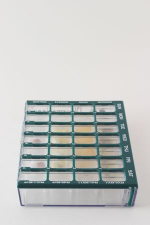 Organizer for medications with compartments for keeping track of daily doses of medicine over a week timespan; organizer pillbox is centered in lower portion of frame with room for added text above the imageの写真素材