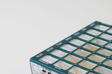 Organizer for medications with compartments for keeping track of daily doses of medicine over a week timespan; partial view of organizer pillbox; weekday text labels run diagonally through the pictureの写真素材