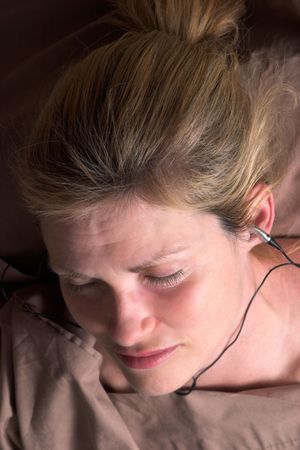Beautiful woman listening to music on headphones and receiving relaxing massage at homeの写真素材