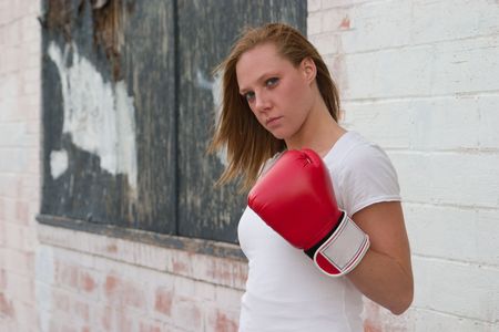 Blond girl on the city streets wearing boxing gloves.の写真素材