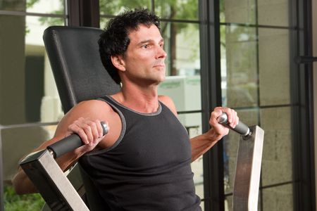 Man exercising his arm muscles on an exercise machine in a fitness center.の写真素材