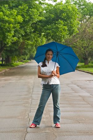 Young beautiful brunette woman holding an umbrella above her head.の写真素材