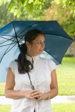 Young beautiful brunette woman holding an umbrella above her head.の写真素材