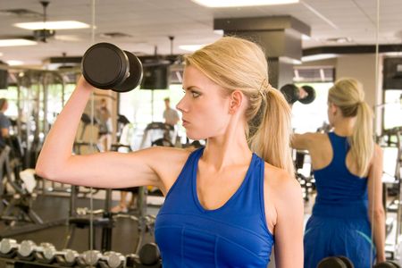 Beautiful blond woman lifting weights in a fitness center.の写真素材