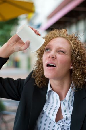 Young business woman in panic trying to get the last drip of coffee from a coffee cup.の写真素材