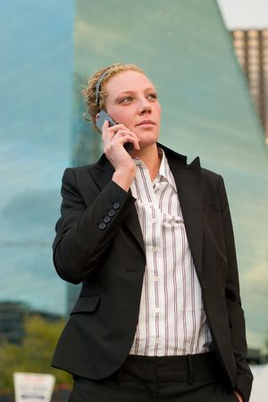 Young business woman talking on a cellphone in front of city skyscrapers.の写真素材