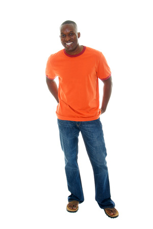 Handsome, happy, smiling man in a casual outfit of orange t-shirt, blue jeans, and sandals.の写真素材