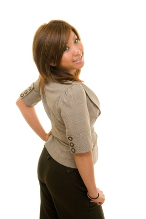 Beautiful young Asian business woman in business suit looks over her right shoulder at the cameraの写真素材