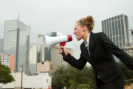 Young business woman making herself heard with a megaphone.の写真素材
